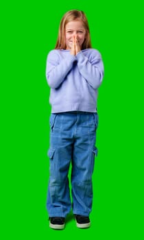 A young child in a cozy sweater and blue cargo pants poses with hands clasped in studio