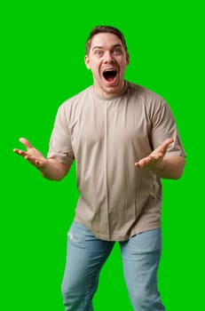 Young man in casual clothing stands with open arms against a vibrant green background in studio