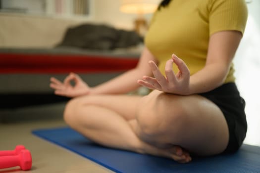 Young woman practicing meditation on yoga mat, focusing on her breathing.