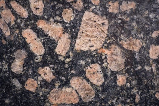 Close-up view of a polished granite surface revealing feldspar crystals embedded in a dark matrix, showcasing natural stone texture.