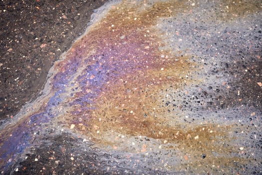 Dazzling oil stain with a spectrum of hues on the asphalt surface
