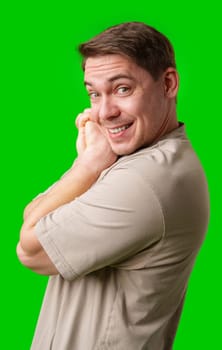A cheerful man with a friendly smile poses against a bright green background in studio