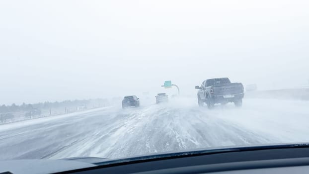 Denver, Colorado, USA-January 15, 2024-Several vehicles face blinding snowfall and slippery conditions while traveling on an interstate, with the storm reducing visibility and the roads boundaries barely discernible.
