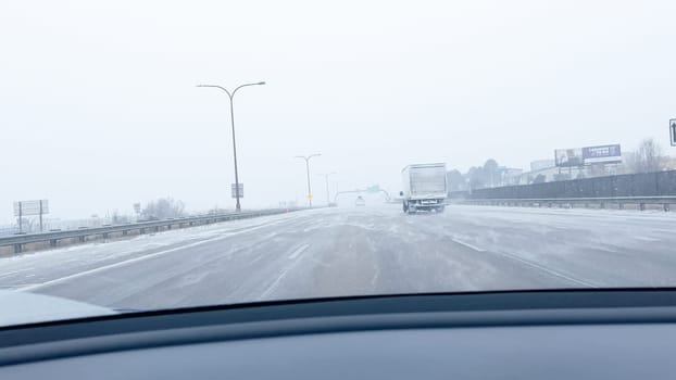Denver, Colorado, USA-January 15, 2024-Several vehicles face blinding snowfall and slippery conditions while traveling on an interstate, with the storm reducing visibility and the roads boundaries barely discernible.