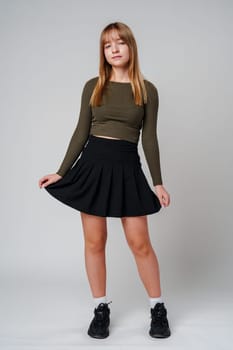 A young woman with straight hair wearing a green top poses against a neutral background in a calm setting