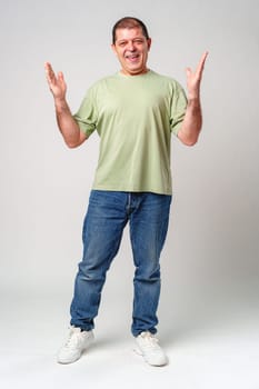 Cheerful man in a green shirt expressing happiness with open hands against a plain background close up