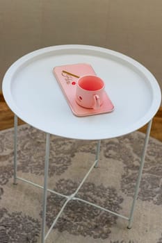 Coffee table with the pink cup for ladies on it.