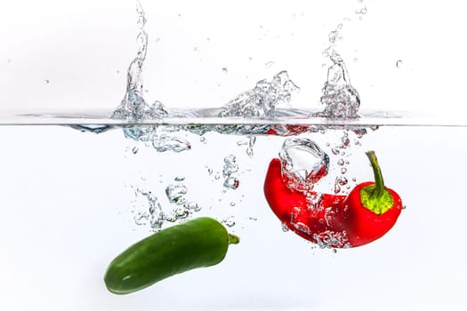 A conceptual image of a red and a green pepper dropped in water.