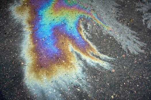 Iridescent oil stain creating a striking rainbow effect on the wet asphalt.