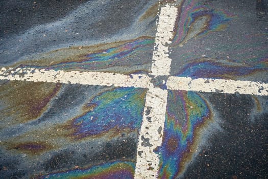 Bright gasoline or oil patch generating a colorful sheen on the asphalt parking surface