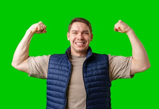 Man celebrating with raised fists in front of a bright green background in studio