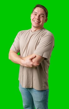 Smiling man in a beige shirt poses against a bright green background in studio