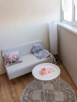 Interior of the balcony of the modern apartment. Sofa, coffee table, standing light