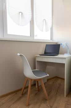 Tiny working space in the apartment. Laptop on the desk