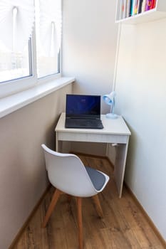 Tiny working space in the apartment. Laptop on the desk.