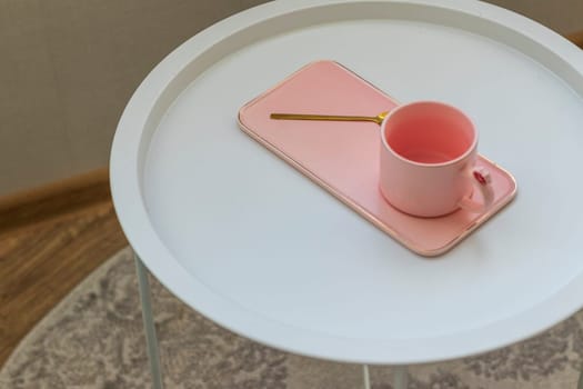 Coffee table with the pink cup for ladies on it. Concept