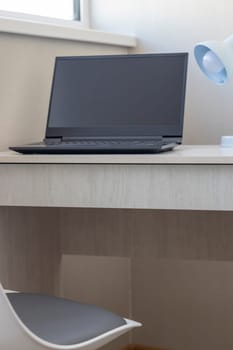 Tiny working space in the apartment. Laptop on the desk.