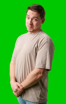 A man smiles thoughtfully while standing against a bright green background in studio