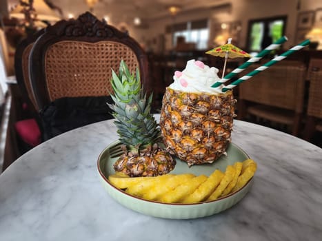 A refreshing pineapple cocktail served in a hollowed out pineapple, topped with whipped cream and a colorful umbrella. A Pinacolada