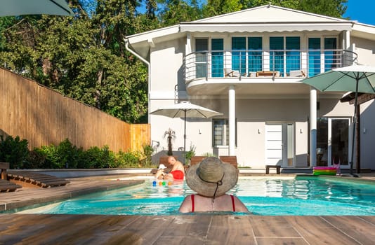 Family with toddler spending a joyful day by the pool at a villa under the sunny sky. Concept of carefree family time, outdoor fun, and happiness together