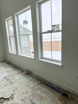 Parker, Colorado, USA-January 11, 2023-Three large windows in a new construction home provide ample natural light The unfinished interior shows construction materials and protective floor covering as the building process continues