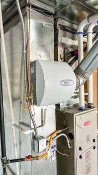 Parker, Colorado, USA-January 11, 2023-Close-up view of an HVAC system with a connected humidifier unit in a newly constructed residential home The image showcases ductwork pipes and electrical components highlighting the mechanical setup in the house