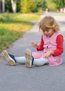 The child fell on the road and hit her leg. Selective focus. kid.