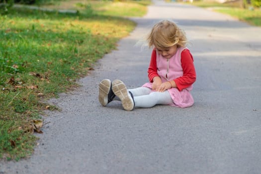 The child fell on the road and hit her leg. Selective focus. kid.
