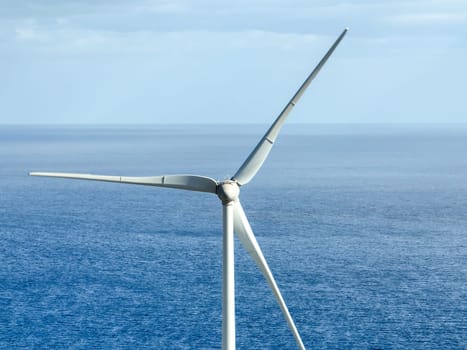 Wind power station with wind turbines, windmill propellers spinning in the wind, closeup view. Development of green ecological alternative energy on the islands of the Atlantic Ocean.