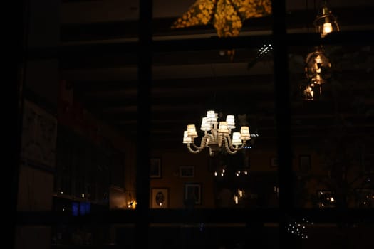 A stunning chandelier casts warm light in a cozy restaurant setting, creating an inviting atmosphere.