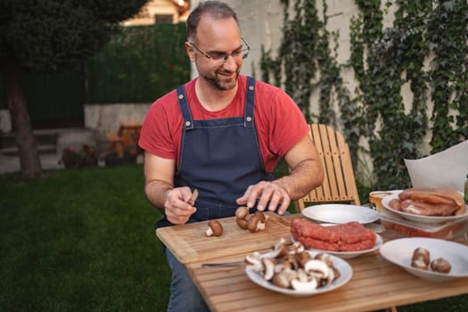 A man joyfully chops mushrooms while enjoying his backyard garden.