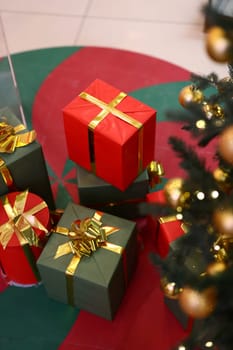 Holiday presents in vibrant red and green are showcased beneath a beautifully decorated Christmas tree