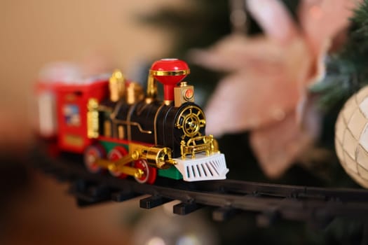 A charming little toy train slides gracefully through vibrant decorations, ideal for festive holiday moments