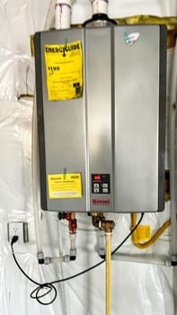 Parker, Colorado, USA-January 11, 2023-A Rinnai tankless water heater installed in the basement of a newly constructed residential home. The energy-efficient unit provides on-demand hot water and features an Energy Guide label for performance specifications.
