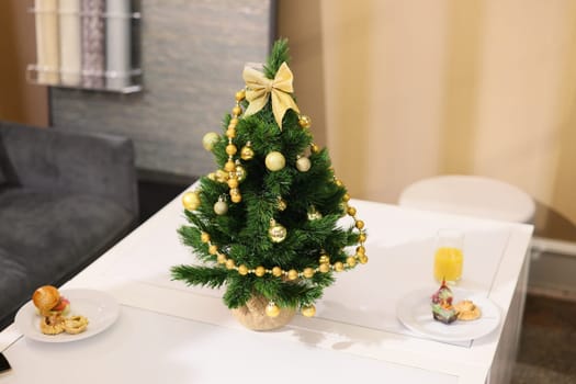 A cozy and festive Christmas table setting featuring a beautifully decorated tree, delicious snacks, and a warm drink