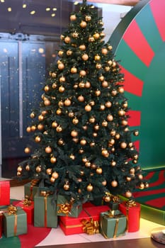 A beautifully decorated Christmas tree adorned with golden ornaments and surrounded by colorful gifts.