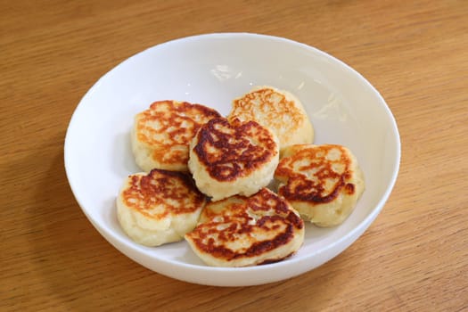 Delicious golden brown cheese pancakes are served in a cozy bowl, making them perfect for breakfast or a snack