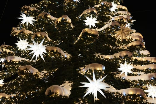 A beautifully decorated Christmas tree, adorned with glowing stars, twinkling lights, and elegant golden accents