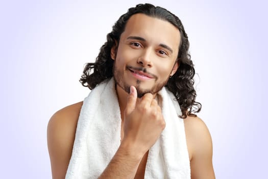 Smiling man with curly hair showing confidence while holding a towel in studio