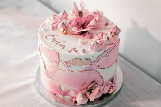 Birthday cake decorated with pink sugar flowers and butterflies. High quality photo