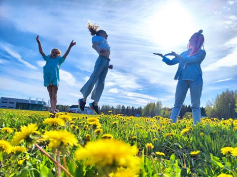 Three children happily leap in a vibrant dandelion field, enjoying the warm sunlight and clear blue sky during spring.