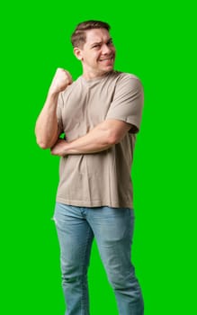 Man celebrating with a confident smile and raised fist against a bright green background in studio