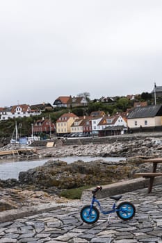 Blue children's bicycle on the beach by the sea in a small town. Bornholm, Denmark - December 5, 2024.