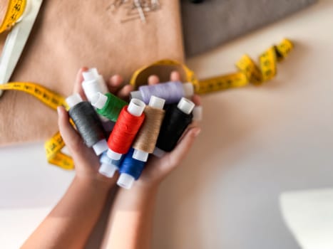 Colorful threads and measuring tape in crafting hands.