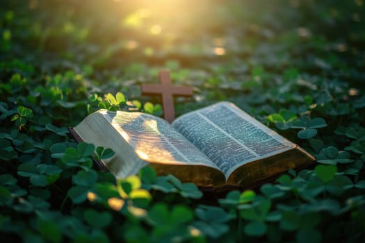 a bible book and a cross lying on the green clover leaves..