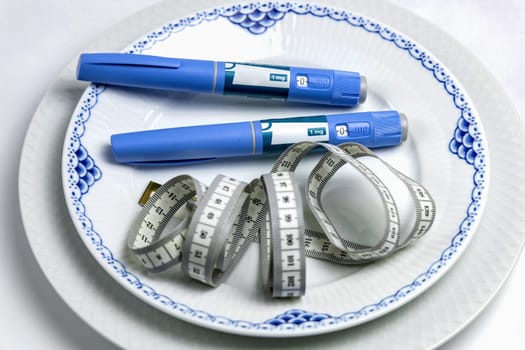 Ozempic Insulin injection pen or insulin cartridge pen for diabetics on a white plate. Medical equipment for diabetes parients.