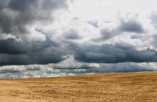 Beautiful background of dramatic sky with clouds and yellow sand. High quality photo