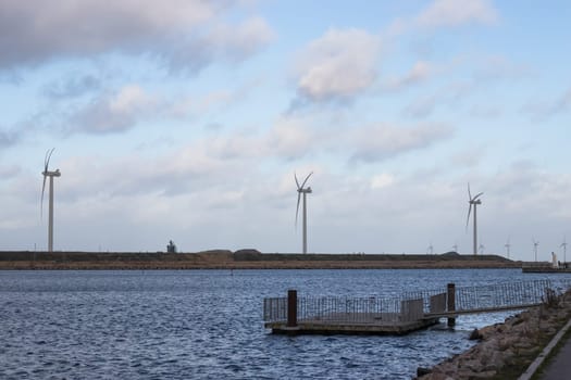 Wind turbine farm power genarator in beautiful nature landscape for production of renewable green energy. High quality photo