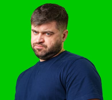Man expressing confusion with crossed arms in front of a bright green background during a casual moment