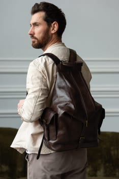 A man in a beige shirt posing with a brown backpack